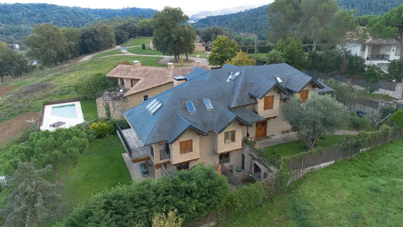 Vista aérea de una casa de piedra con tejado de pizarra en un entorno natural