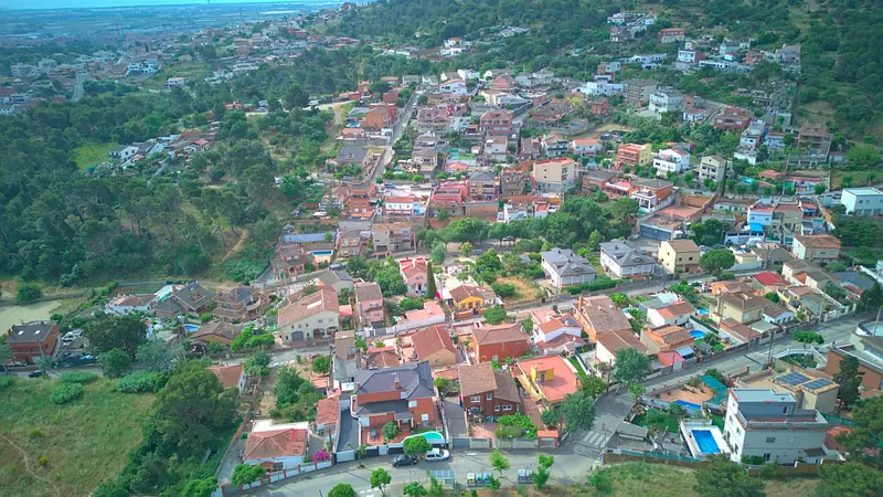 Vista aérea de una urbanización de casas unifamiliares rodeada de bosque