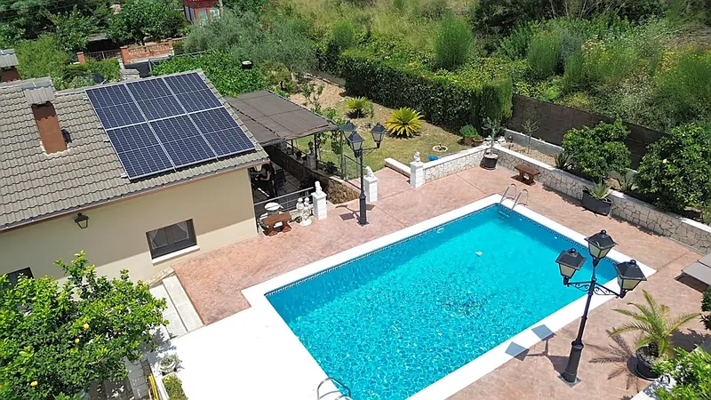 Vista aérea de una vivienda con piscina, jardín y placas solares
