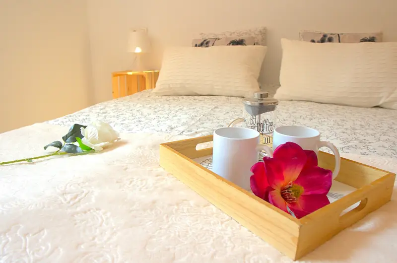 Detalle de dormitorio con bandeja de desayuno sobre la cama