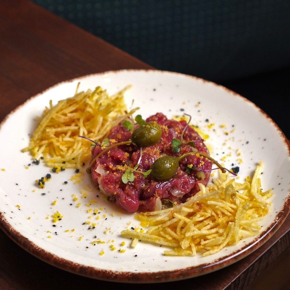 Plato de tartar de carne con patatas paja servido en restaurante de Barcelona, fotografía profesional para hostelería.