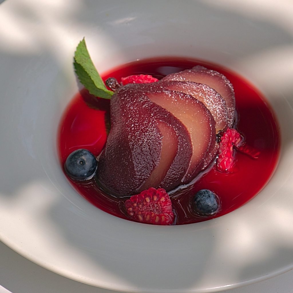 Postre gourmet con peras al vino y frutos rojos, ejemplo de fotografía gastronómica profesional en Barcelona