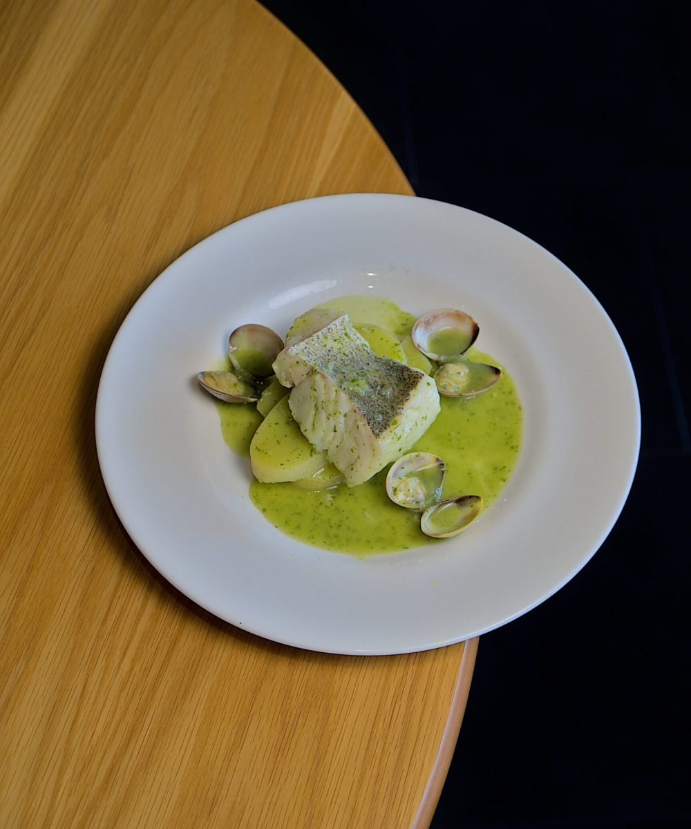 Fotografía profesional de plato de bacalao con almejas en salsa verde, ideal para restaurantes de Barcelona.