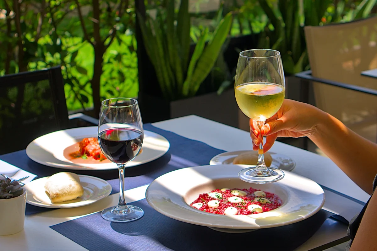 Carpaccio servido en terraza con copas de vino blanco y tinto – fotografía gastronómica Click Lab